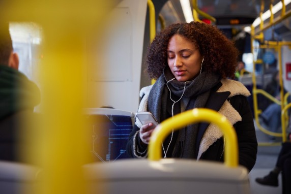 En kvinna sitter i en buss och tittar på sin mobil