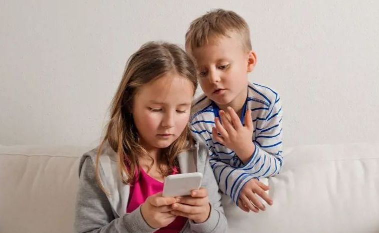 Två barn tittar på mobiltelefon